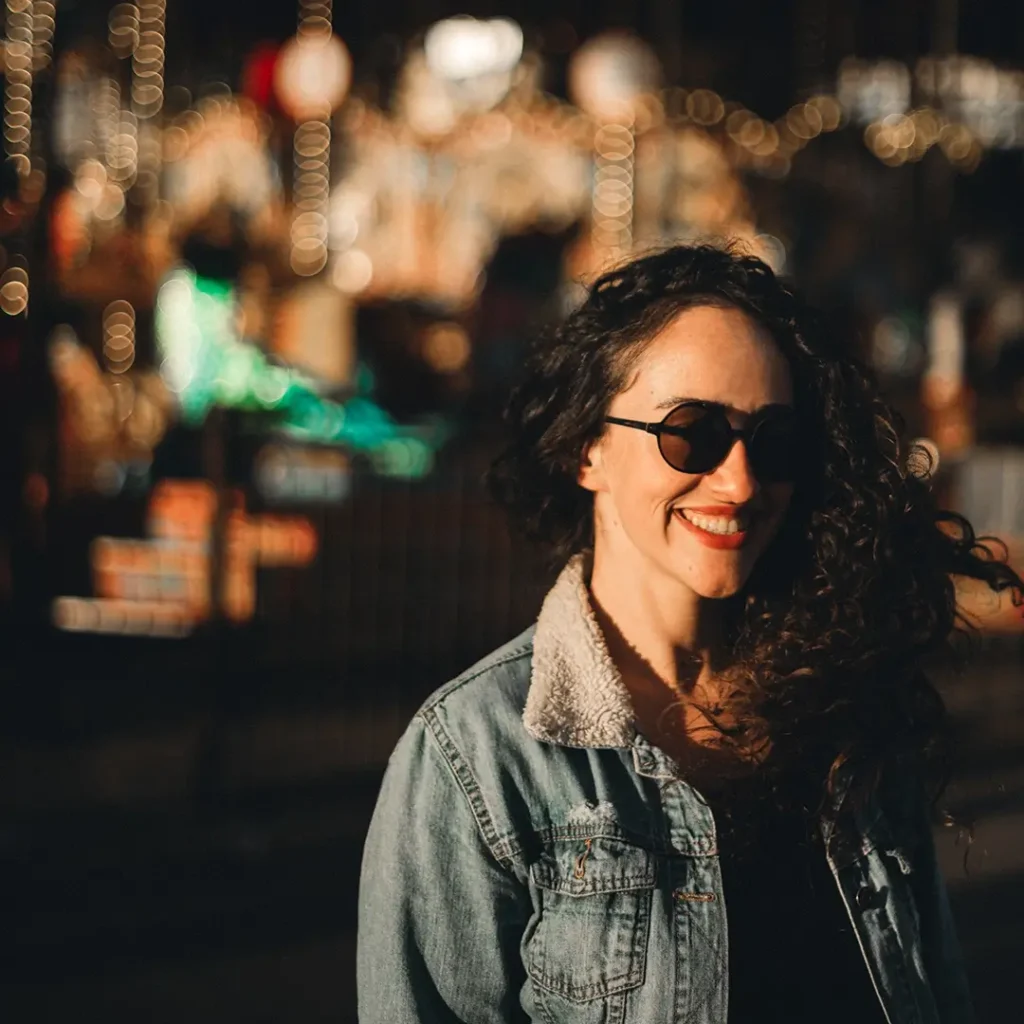 Marina Assis smiling in London at night, with city lights in the background
